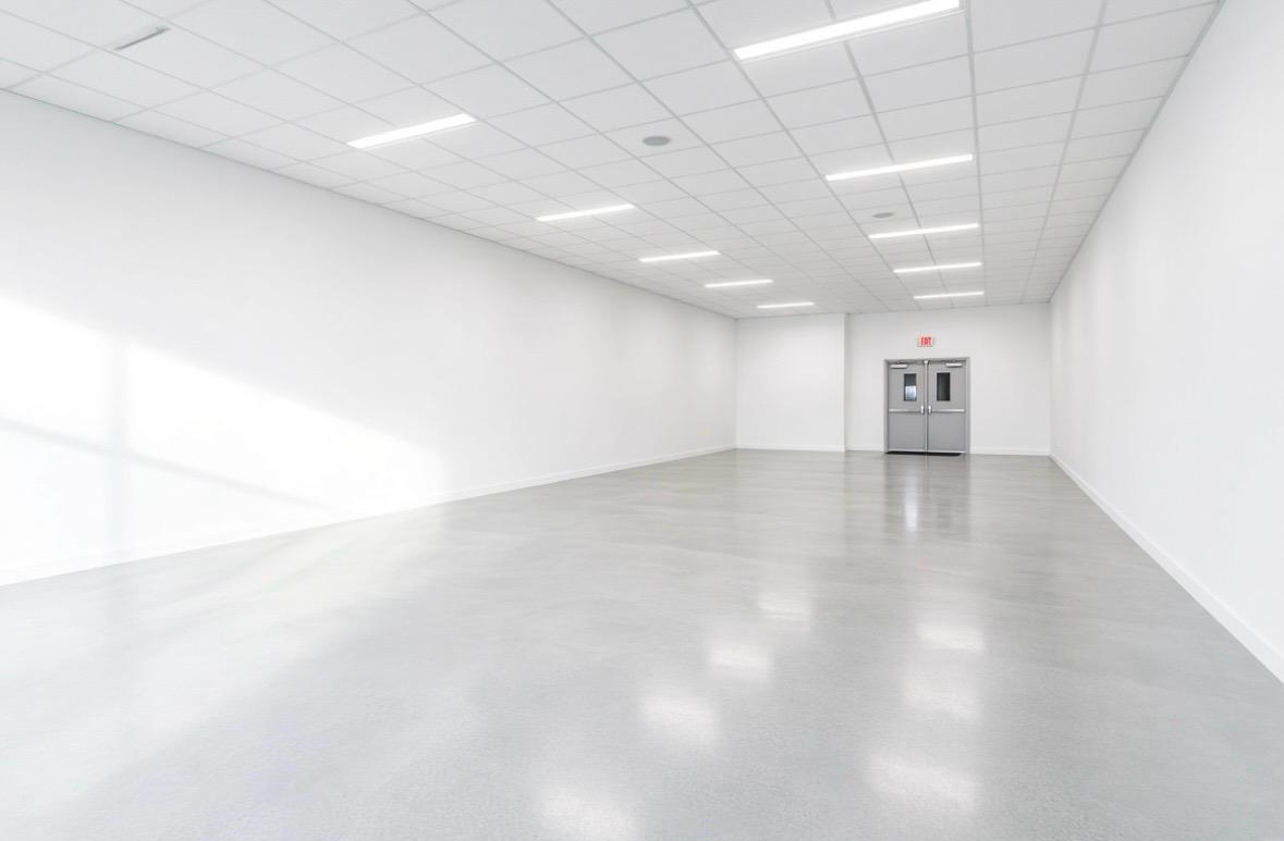A commercial unit in white-box condition: tenant fit-out stripped out, surfaces made good, walls and ceiling coated in clean neutral white, ready to re-let.